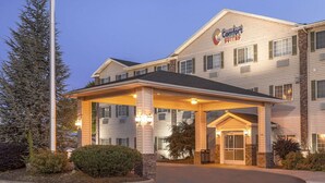 Ein Comfort Suites Hotel mit überdachter Zufahrt, mehreren Fenstern und einer gut beleuchteten Fassade.