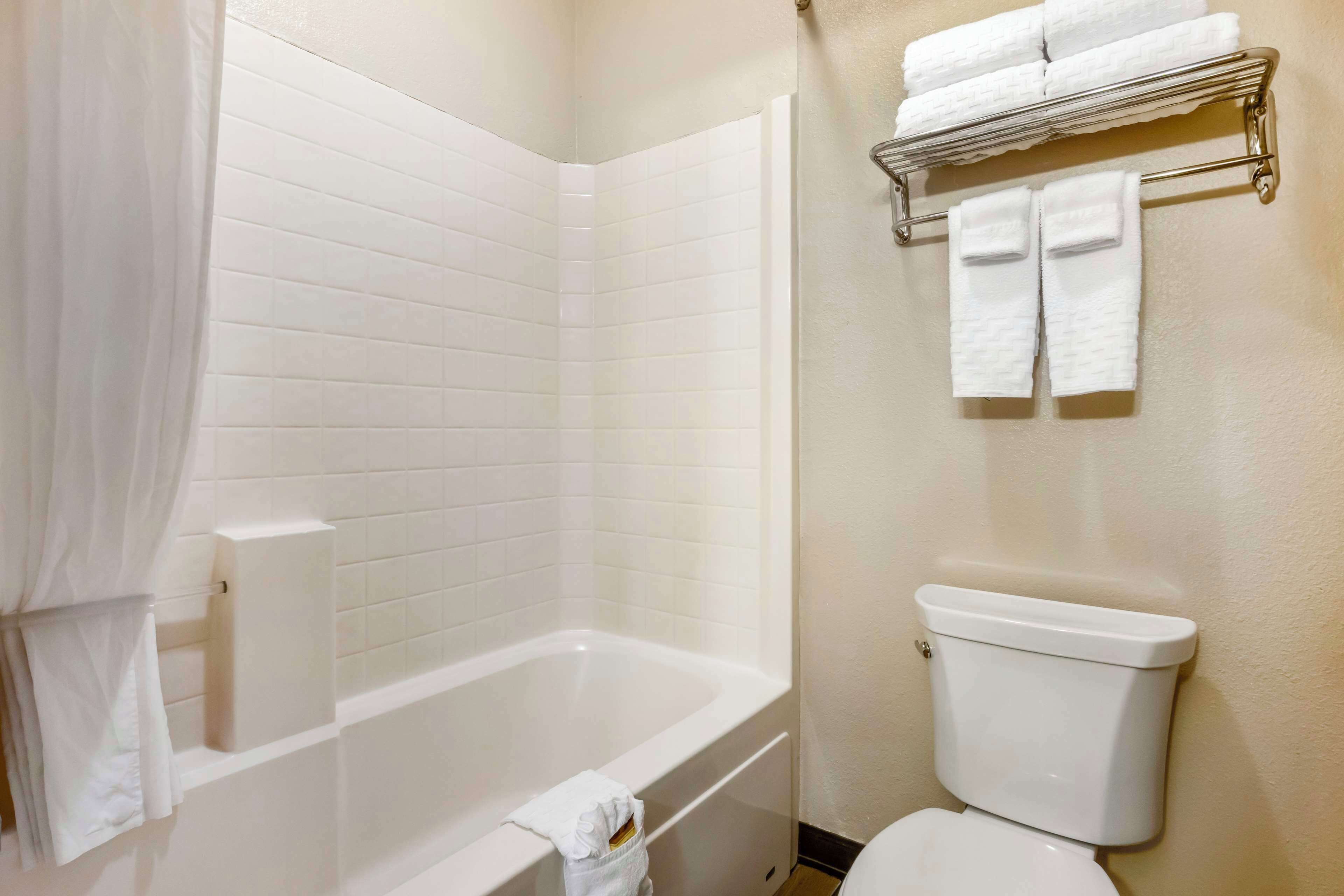 Un baño con bañera, inodoro y un perchero con toallas.