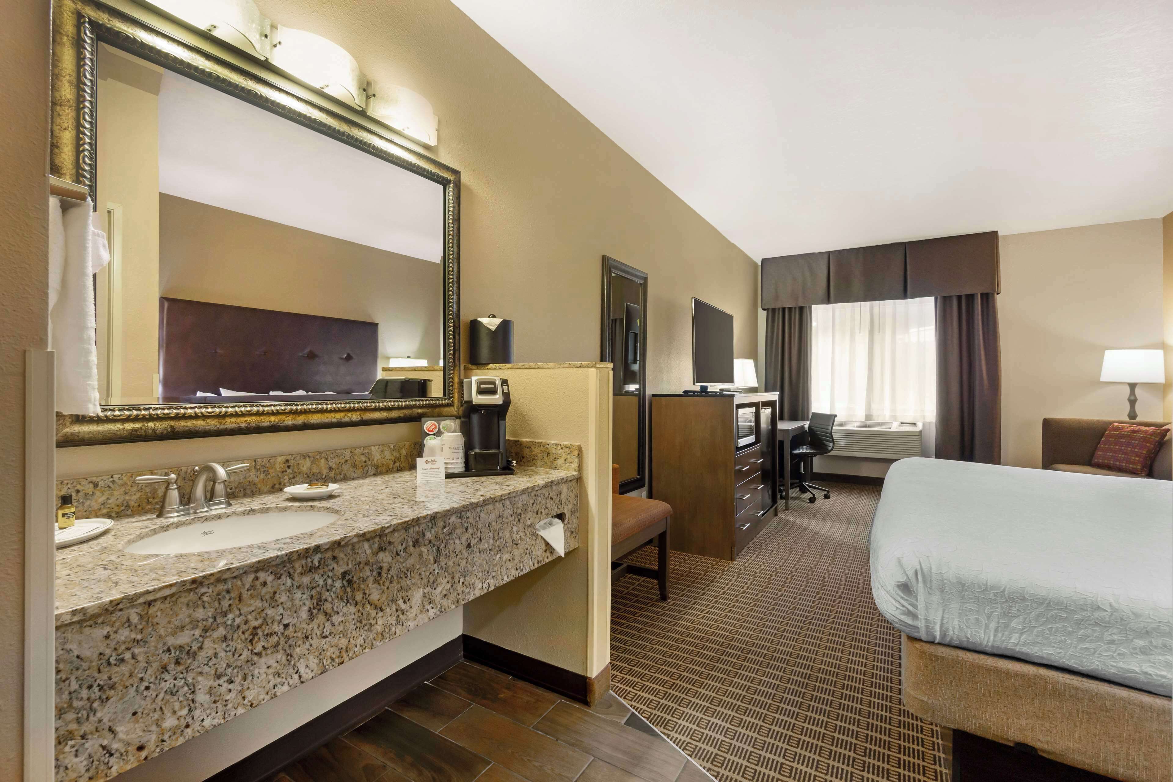 Ein Hotelzimmer mit großem Waschtisch, einem Bett, einem Schreibtisch und einem Fernseher.