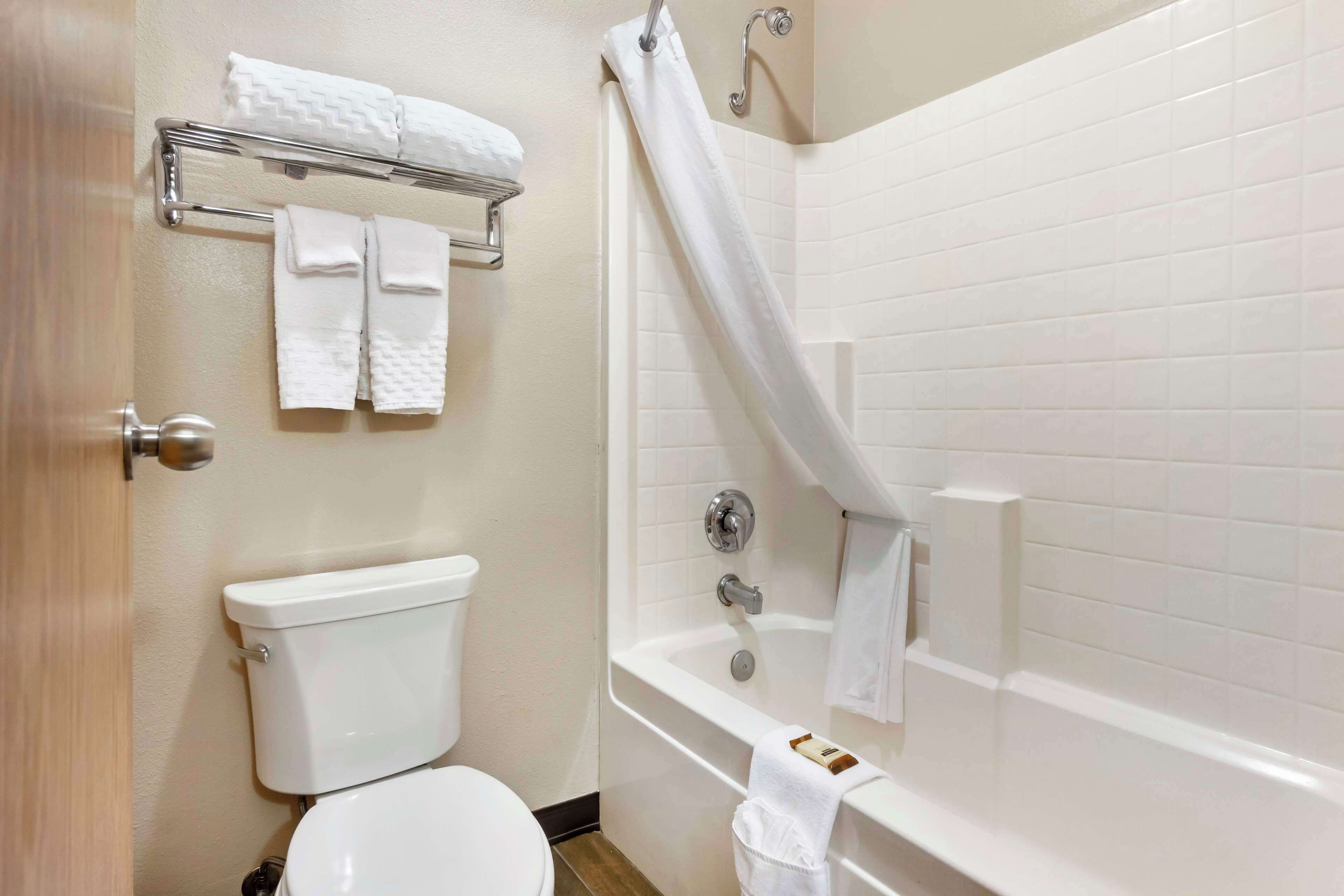 A bathroom with a toilet, a bathtub, and a towel rack with folded towels.