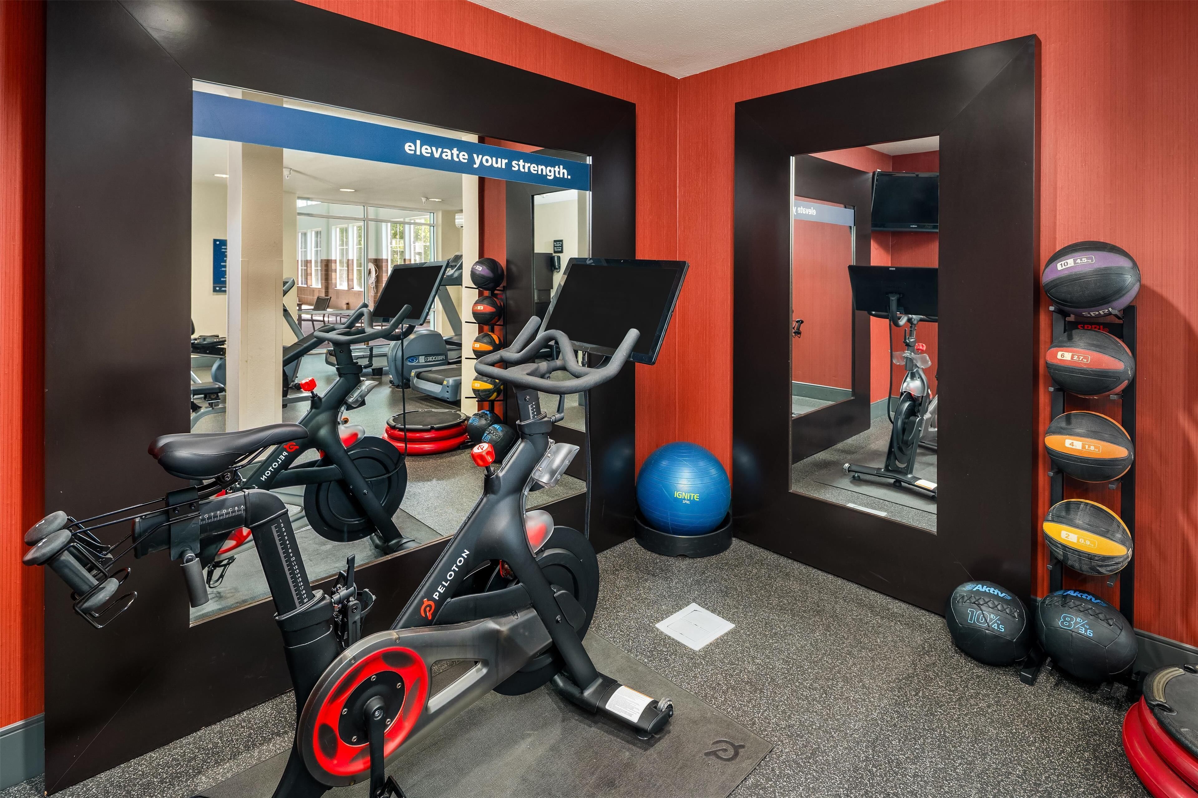 Une salle de sport équipée de matériel d’exercice, d’un miroir et d’une affiche motivante.