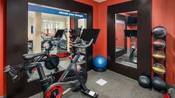 Un gimnasio con equipo de ejercicio, un espejo y un cartel motivacional.