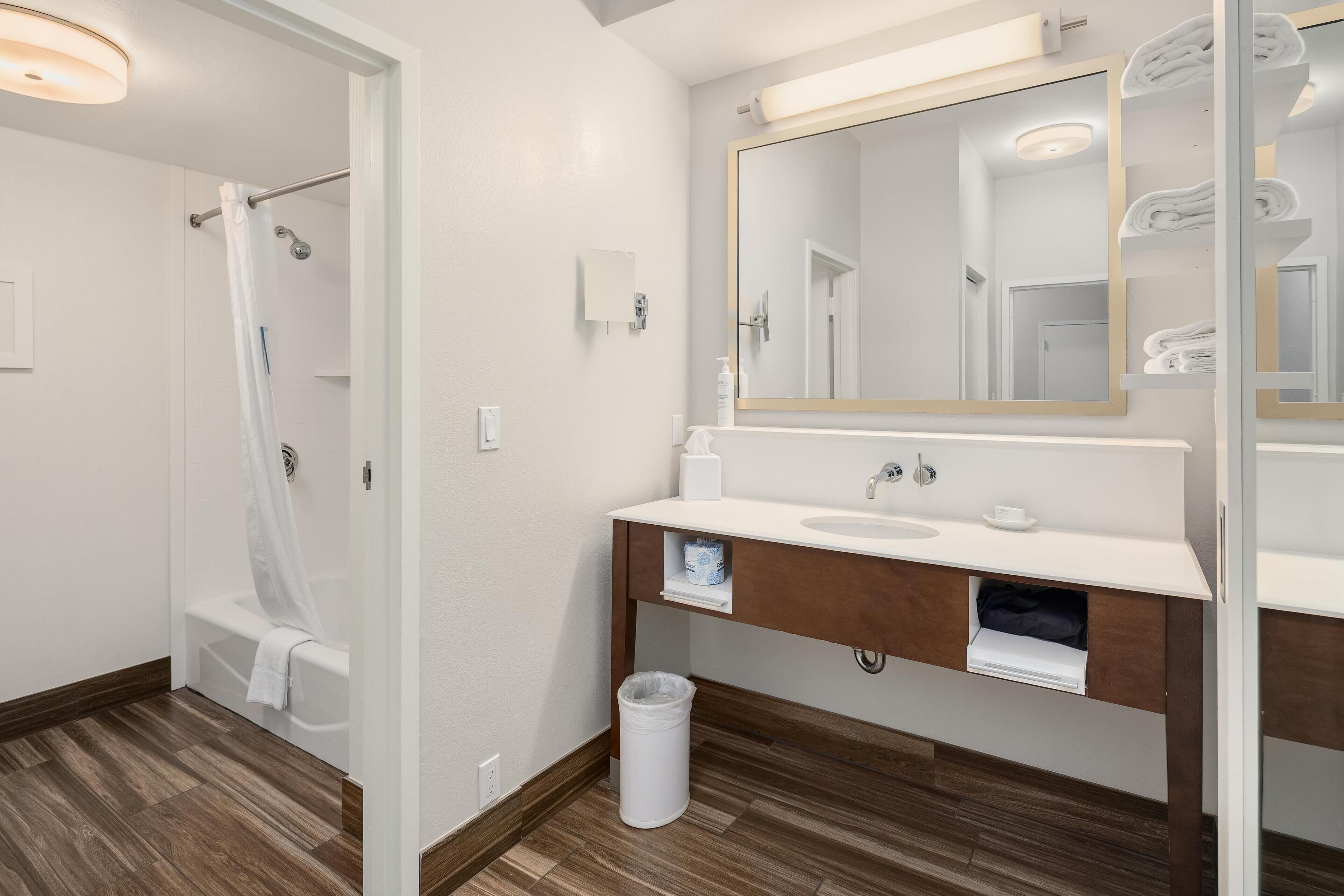 A modern bathroom with a shower, a sink, and a mirror.