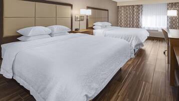 A hotel room with two beds, a desk, and a chair.