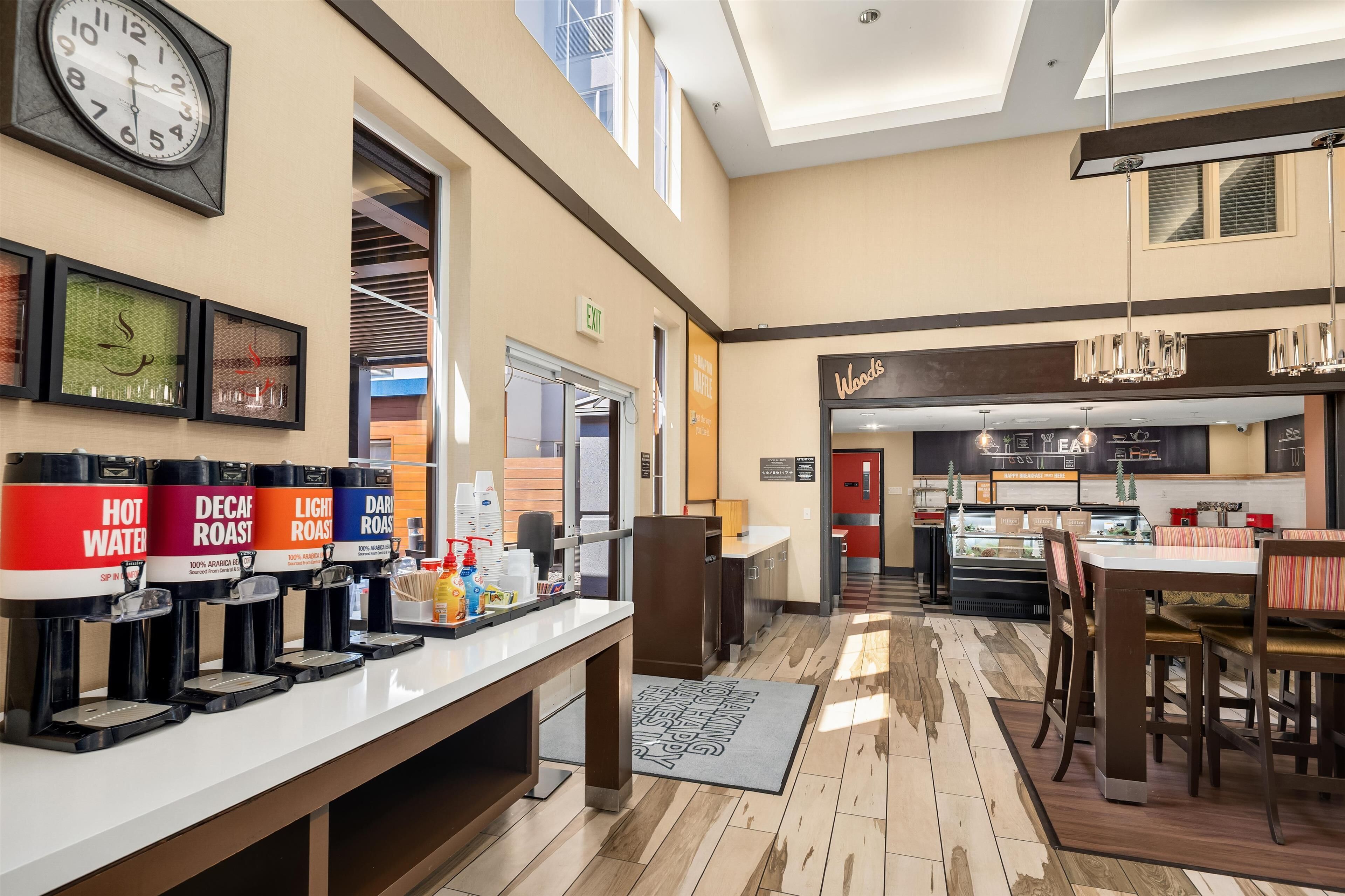 Eine Hotelhalle mit Kaffeebar, einer Uhr und einem Restaurantbereich.