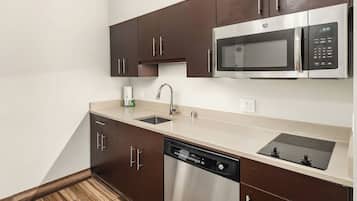 A modern kitchen with dark brown cabinets, a stainless steel microwave, a dishwasher, and a double sink.