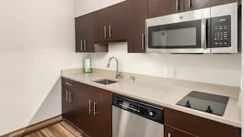 A modern kitchen with dark brown cabinets, a stainless steel microwave, a dishwasher, and a double sink.