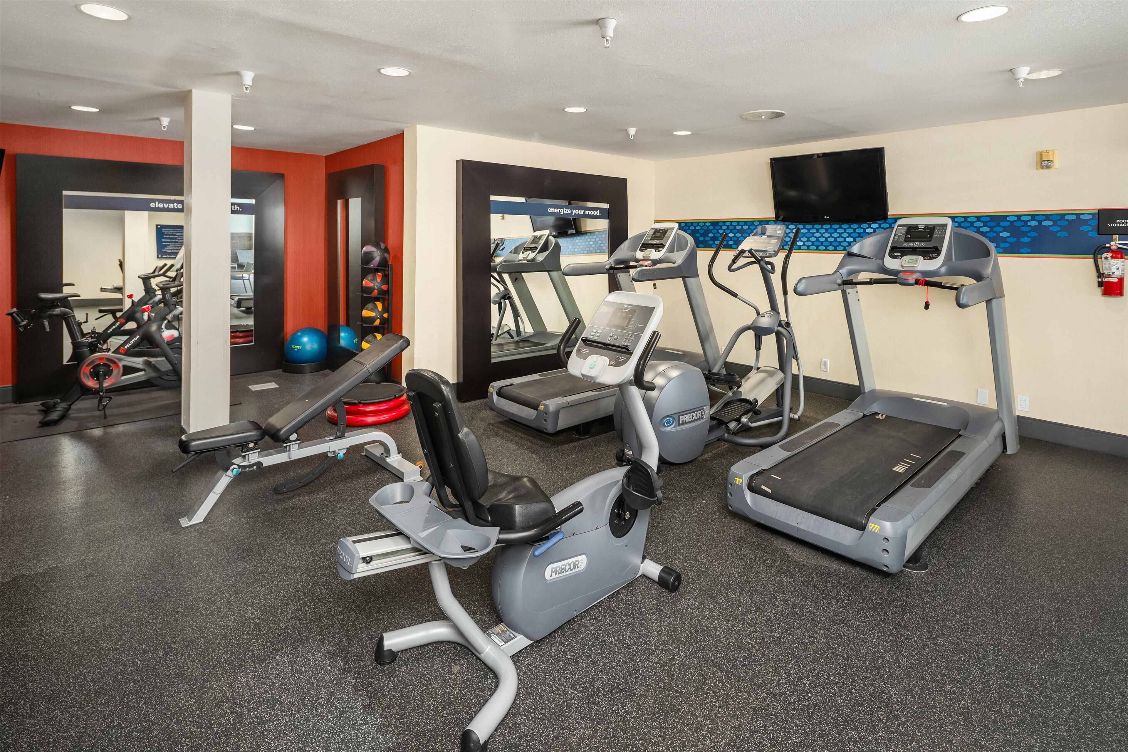 Une salle de sport équipée de tapis de course, de vélos elliptiques et de poids libres.