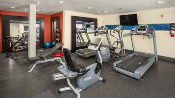 Un gimnasio con cintas de correr, elípticas y pesas sueltas.