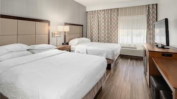 Une chambre d’hôtel avec deux lits, une télévision et un bureau.