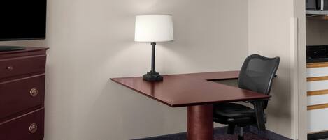 Une salle de conférence équipée d’un bureau, d’une lampe, d’une chaise et d’une commode.