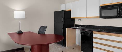 Cocina compacta con mesa, refrigerador, microondas y lavavajillas.