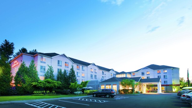 A multi-story hotel with a garden inn sign, a parking lot, and a well-maintained lawn. - Hilton Garden Inn Seattle/Renton (Renton)