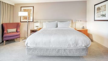 A hotel room with a large bed, a chair, a nightstand, and a lamp.