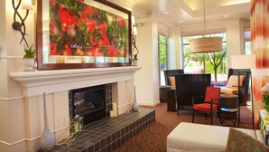 A modern living room with a fireplace, a large painting, and comfortable seating. - Hilton Garden Inn Seattle/Renton (Renton)