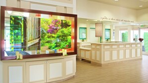 A reception area with a large digital display, a reception desk, and a wall with a quote about nature and imagination. - Hilton Garden Inn Seattle/Renton (Renton)