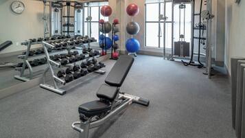 Un gimnasio con equipo de levantamiento de pesas, pelotas de ejercicio y una banca.
