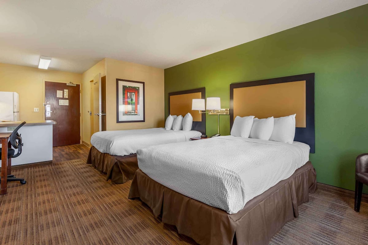 Une chambre d’hôtel avec deux lits, un bureau et une chaise.