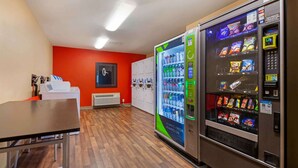 Une pièce avec un distributeur automatique, une table et un mur rouge.