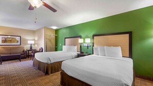 Une chambre d’hôtel avec deux lits, un bureau, une chaise, une lampe et un ventilateur de plafond.