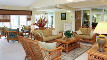 A spacious living area with wicker furniture, a fireplace, and a view of the outside.