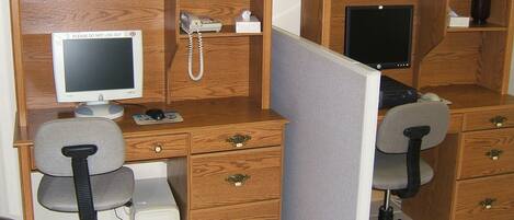 Un cubículo de oficina de madera con una computadora de escritorio, un teléfono y una lámpara de escritorio.