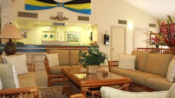 A hotel lobby with a reception desk, registration area, and a seating area with sofas and chairs.