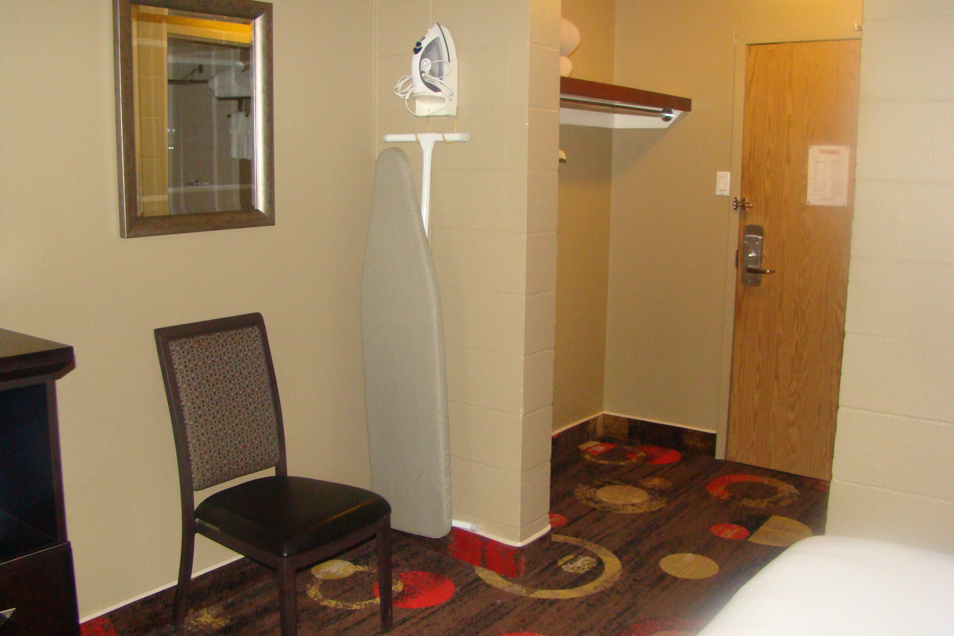 Habitación de hotel con una silla de madera, zona de ducha y una puerta con cerradura.