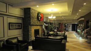 A spacious lobby with a fireplace, leather seating, and a Christmas tree. - Stonebridge Hotel (Fort McMurray)