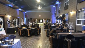 A banquet hall with tables set for a formal event, featuring black and gold decorations. - Stonebridge Hotel (Fort McMurray)