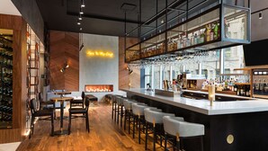 A modern bar area with a long counter, bar stools, and a wine rack.