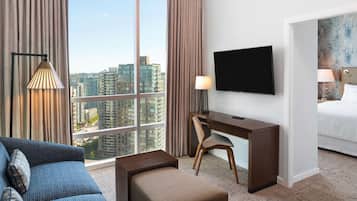 Une chambre d’hôtel dotée d’une grande fenêtre, d’un téléviseur à écran plat, d’un bureau, d’une chaise, d’un canapé et d’un lit.