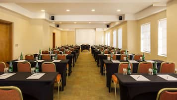 A conference room with rows of tables, chairs, and water bottles.