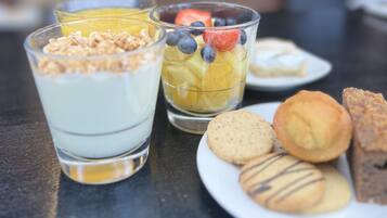 A table with three glasses of fruit parfait and a plate with cookies and pastries.