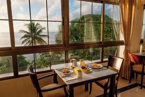 A dining area with a table set for breakfast, overlooking a tropical landscape with palm trees and a view of the sea. - Eurostars Grand Cayacoa (Samaná)