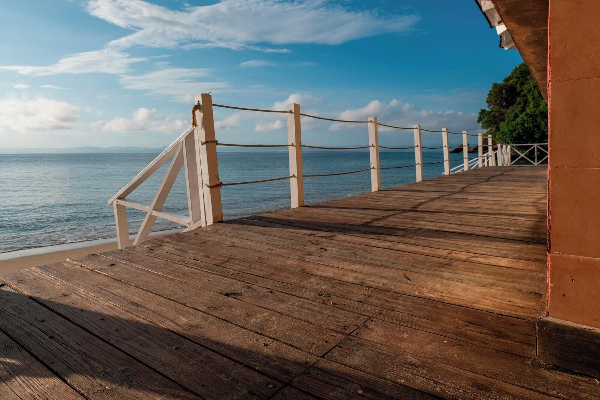 A wooden pier extending to a beach with a clear view of the ocean.