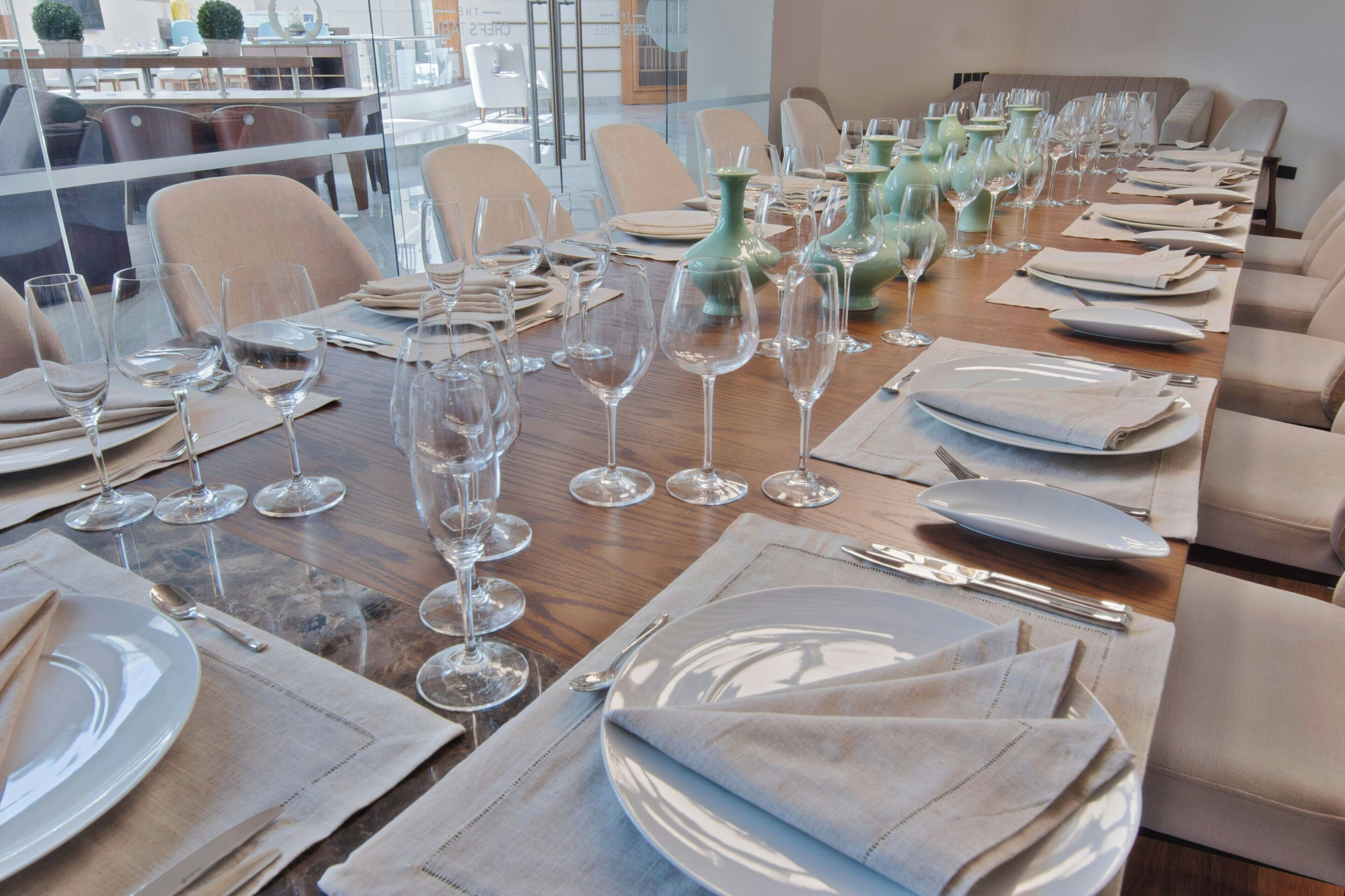 Un espace repas avec plusieurs tables mises pour le repas, chacune étant agrémentée d’assiettes, de couverts et de verres à vin.