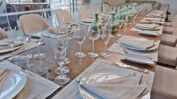 Un espace repas avec plusieurs tables mises pour le repas, chacune étant agrémentée d’assiettes, de couverts et de verres à vin.
