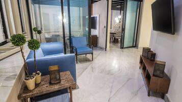 Uma sala de estar moderna com um sofá azul, uma mesa de centro de madeira e uma TV fixada na parede.