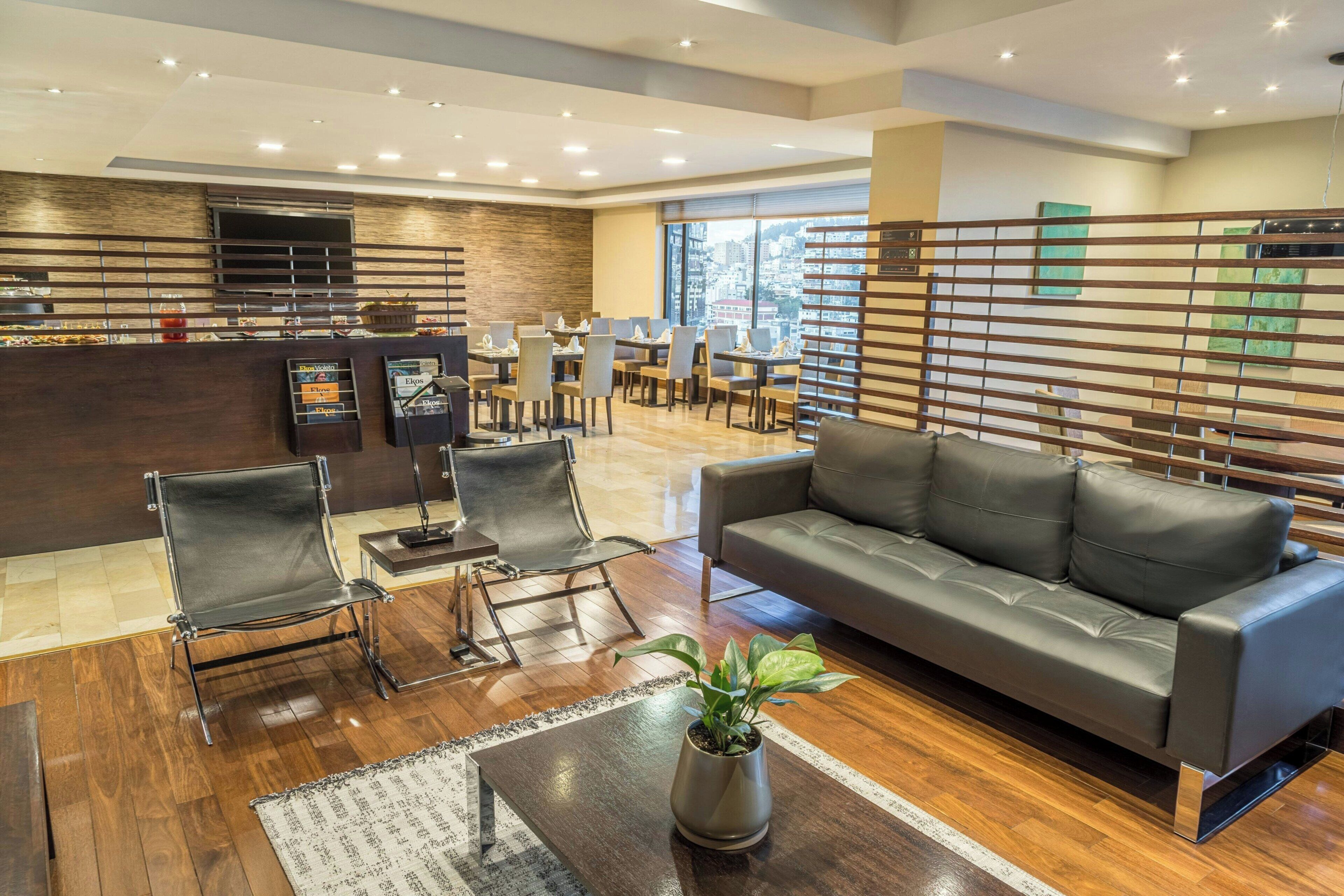 Un moderno vestíbulo de hotel con recepción, zona de estar y un amplio ventanal con vistas a la ciudad.
