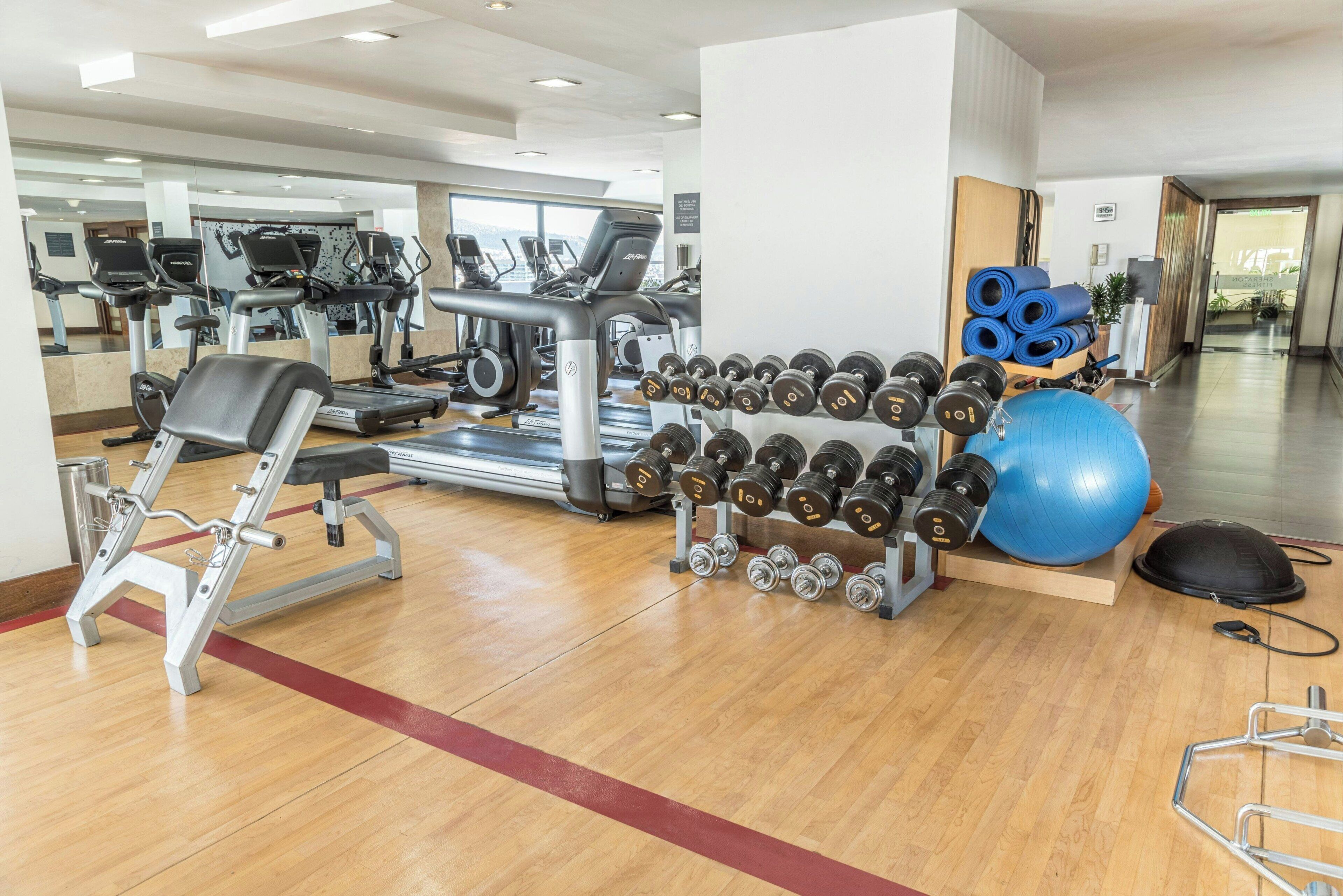 Una palestra con macchinari cardio, manubri e palle da ginnastica.