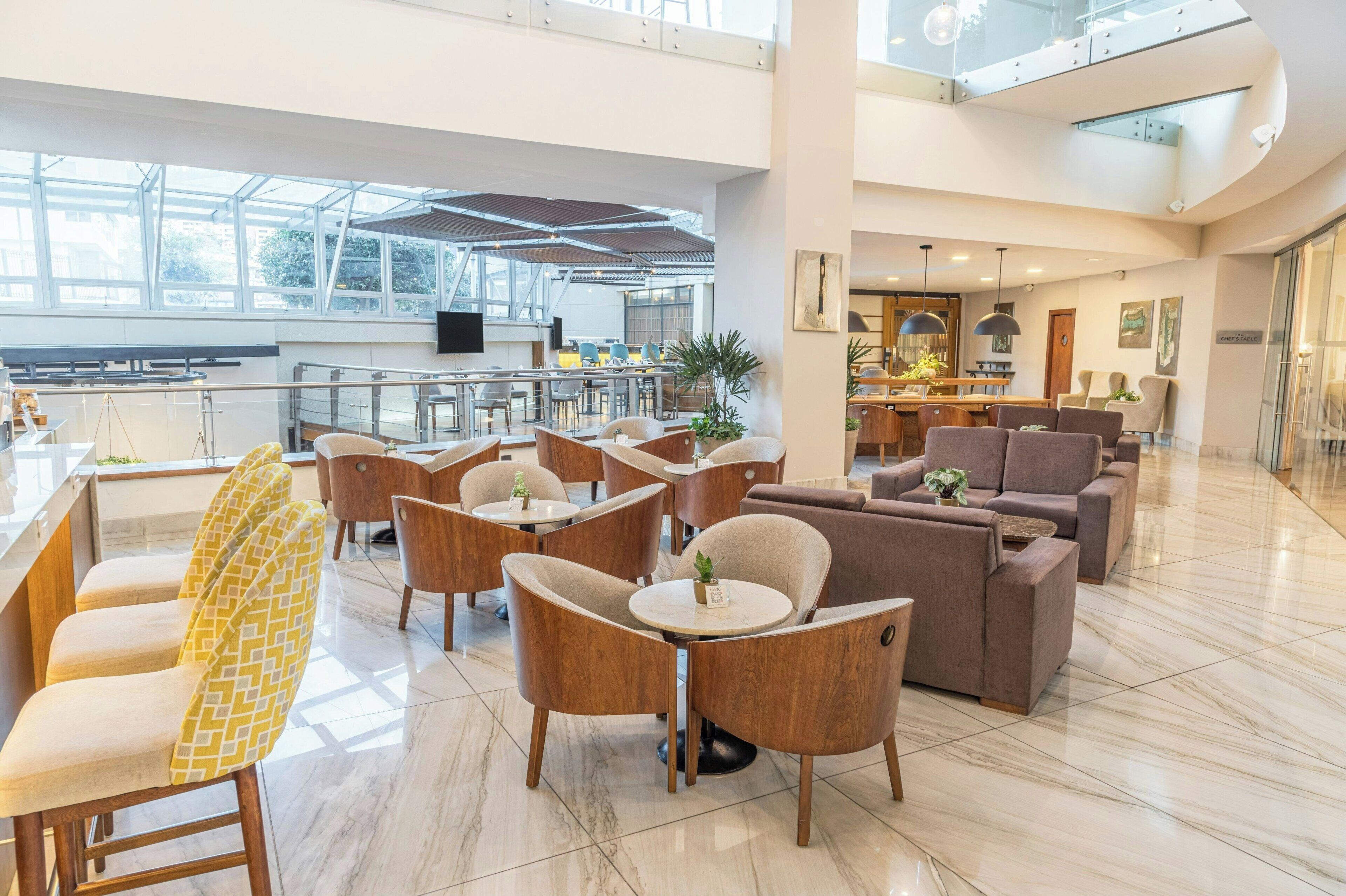 Un'ampia hall con soffitto alto, arredi moderni e un'area bar centrale.
