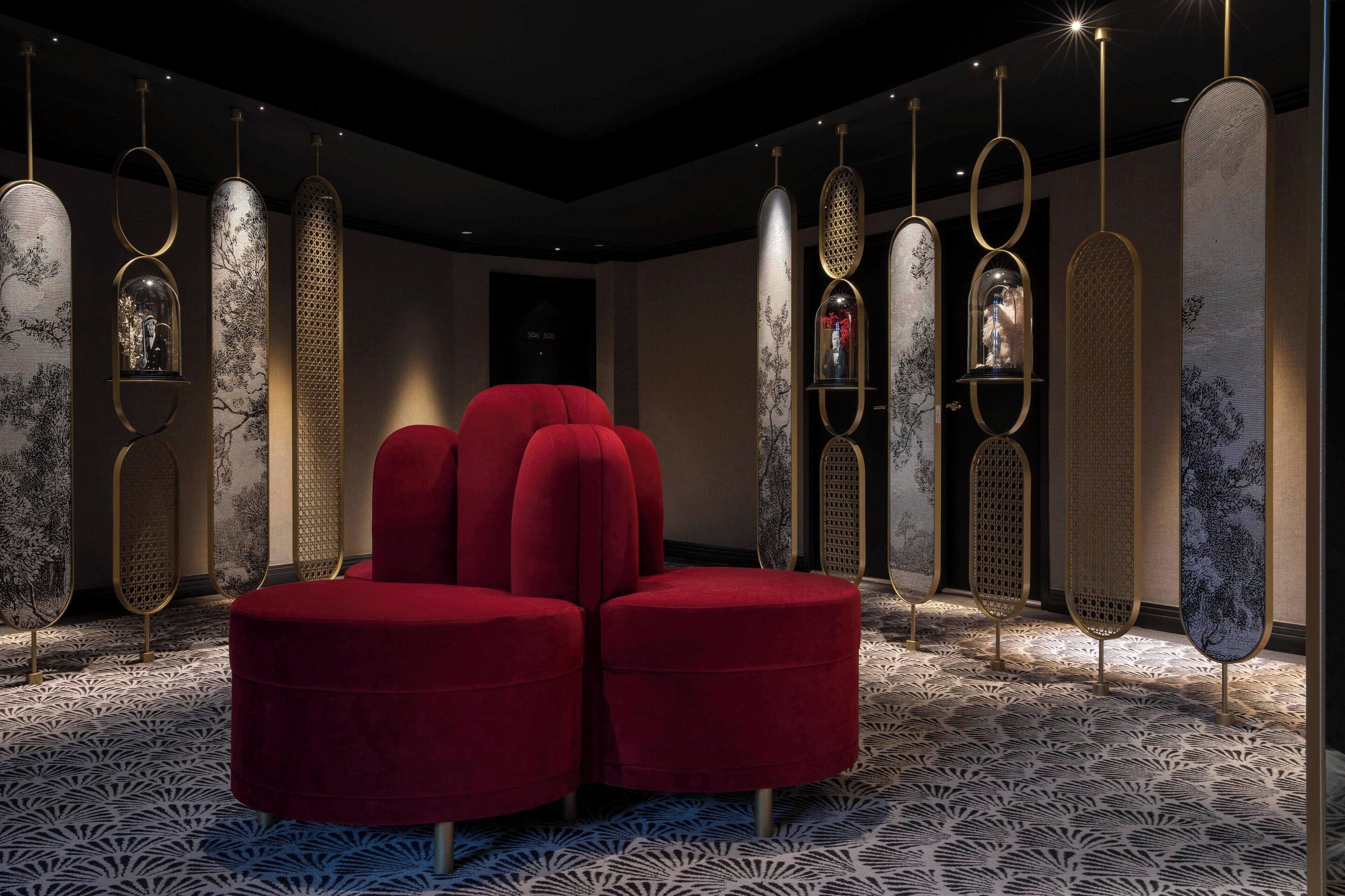 A modern interior with a red upholstered seating area, patterned floor, and decorative panels with embedded lights.