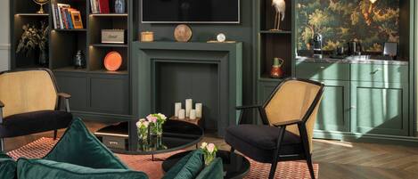 A modern living room with a fireplace, a flat-screen TV, and a bookshelf.