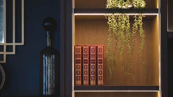 Ein Bücherregal aus Holz mit Büchern, einem gerahmten Kunstwerk und einer hängenden Pflanze.