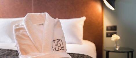 A neatly made bed with a patterned bedspread and a folded white towel with a logo on it.