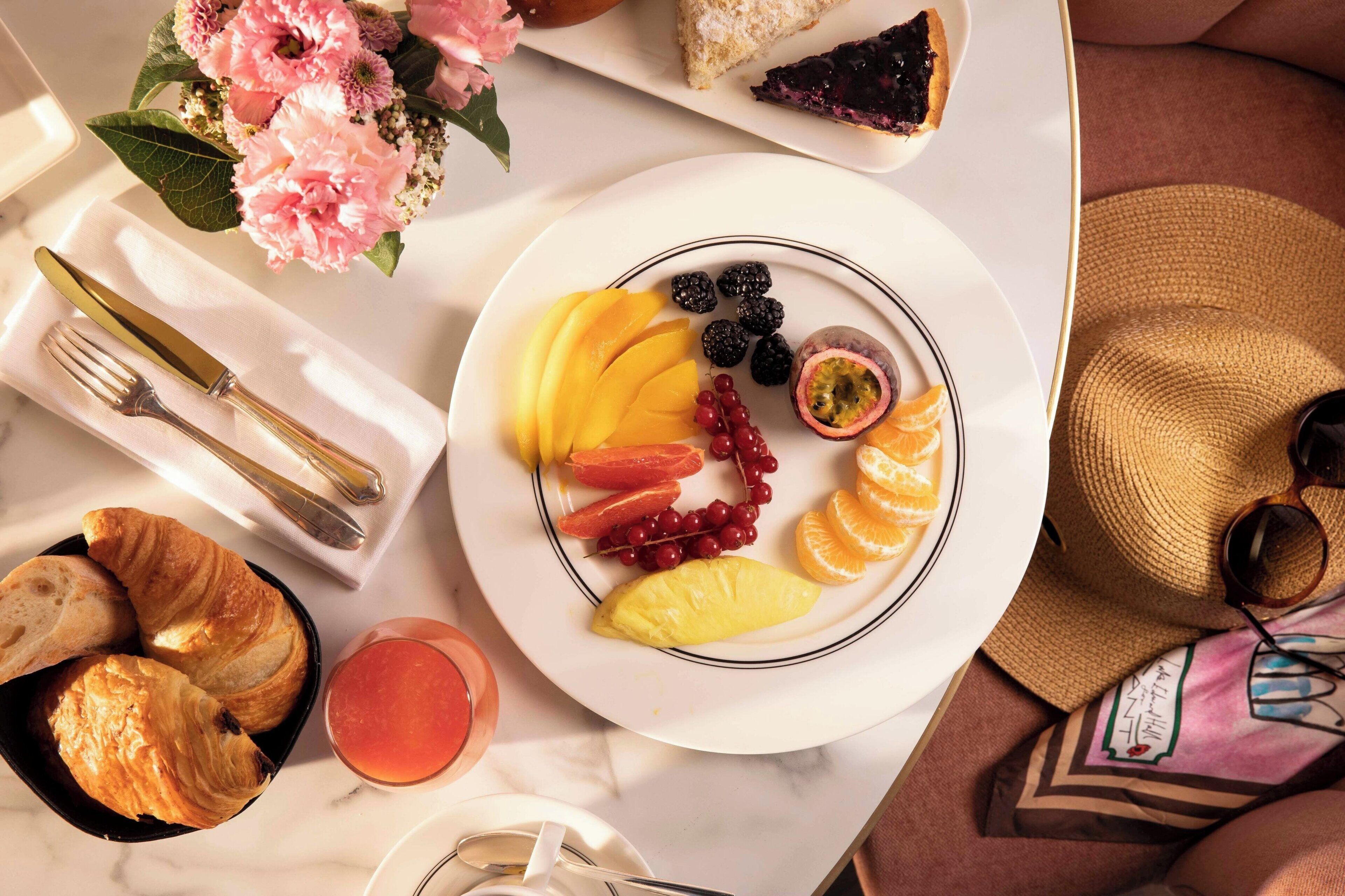 A breakfast setting with croissants, fruit, and a drink on a table.