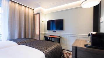 Une chambre d’hôtel avec deux lits, un bureau, une télévision et une machine à café.