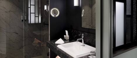 A modern bathroom with a glass-enclosed shower, a white sink, and a large mirror.