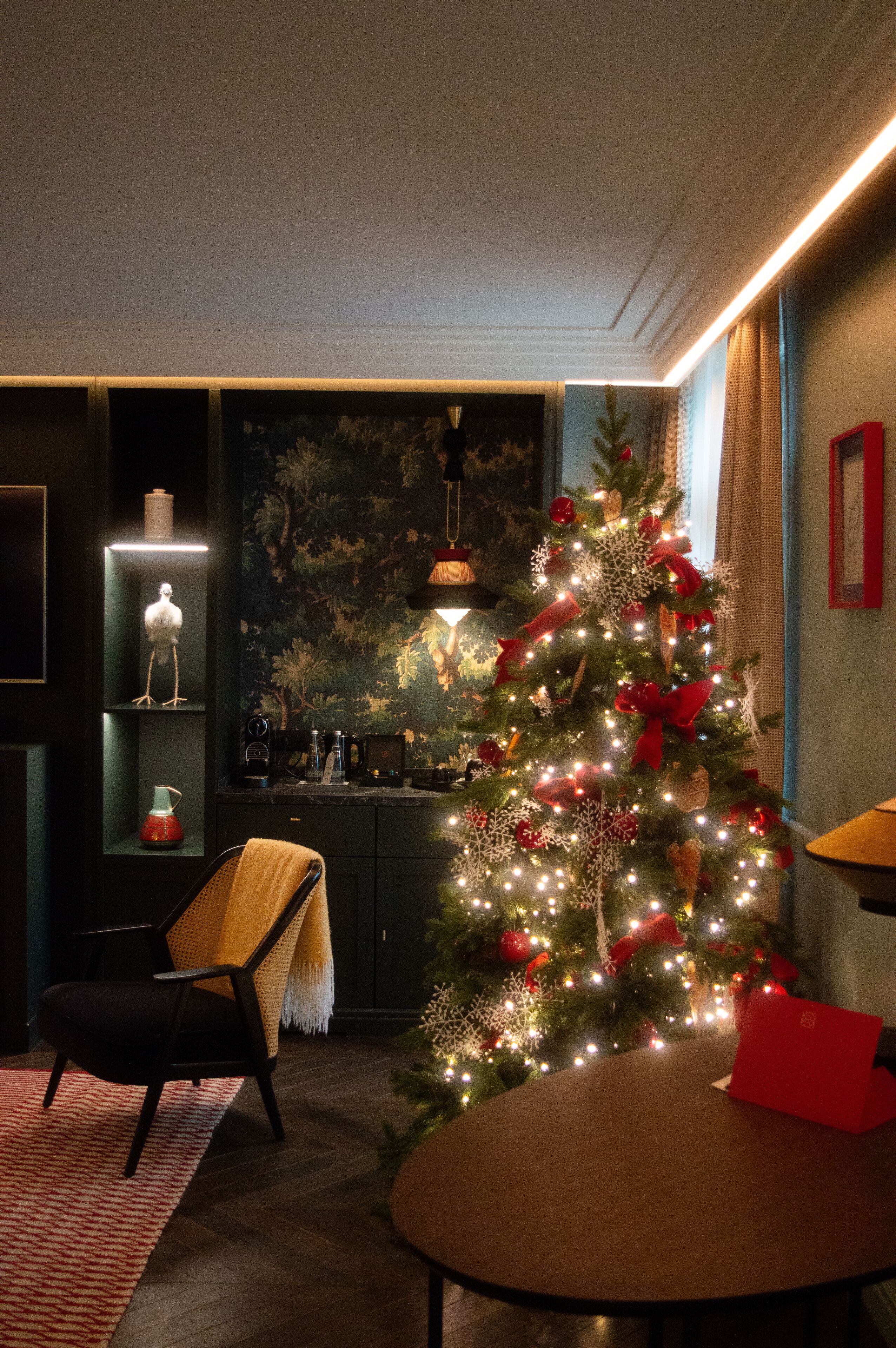 A cozy living room with a Christmas tree, a round table, and a dark-colored sofa.